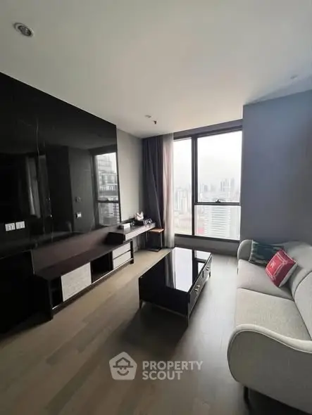 Modern living room with sleek furniture and panoramic city view from large windows.