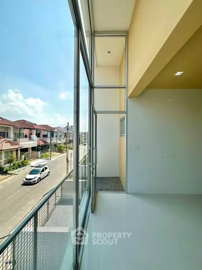 Spacious balcony with large glass windows offering a stunning street view in a modern residential area.