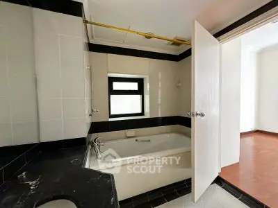 Spacious bathroom with modern bathtub and sleek black and white tiles.