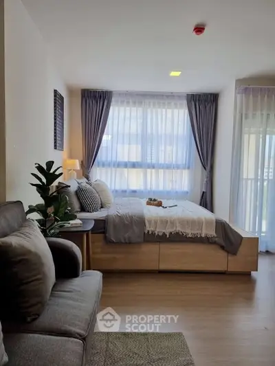 Modern bedroom with cozy decor and large windows for natural light.