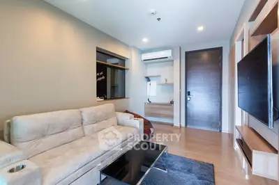 Modern living room with beige sofa, wall-mounted TV, and sleek wooden flooring.