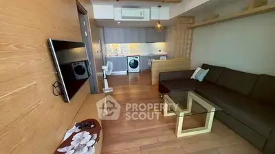 Modern living room with open kitchen and washing machine, featuring wooden flooring and stylish decor.