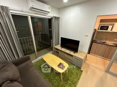 Modern living room with balcony view, featuring sleek furniture and open kitchen layout.