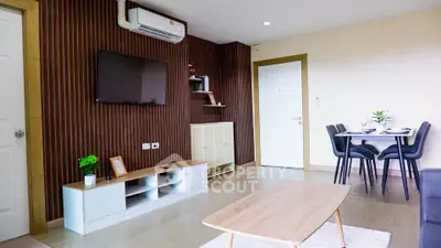 Modern living room with stylish decor and dining area, featuring a sleek TV setup and air conditioning.