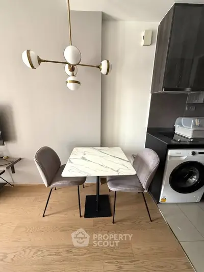 Modern kitchen with marble table, stylish chairs, and washing machine in sleek apartment.