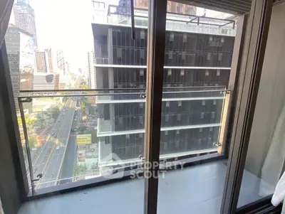 Modern city view from a high-rise balcony with glass railing.