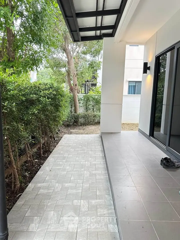 Modern outdoor patio with tiled flooring and lush greenery, perfect for relaxation and entertaining.