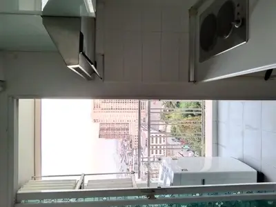 Compact kitchen with city view and washing machine in modern apartment