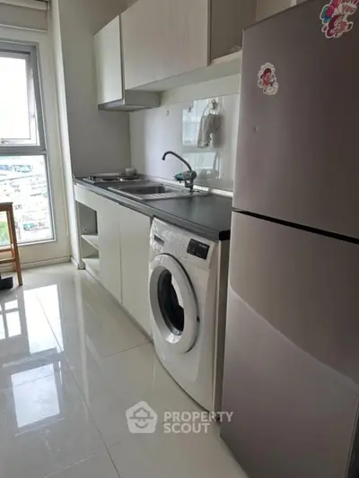 Modern kitchen with washing machine and fridge in bright apartment