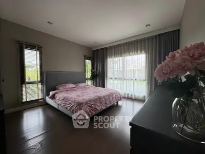 Spacious bedroom with elegant decor and large windows offering natural light.