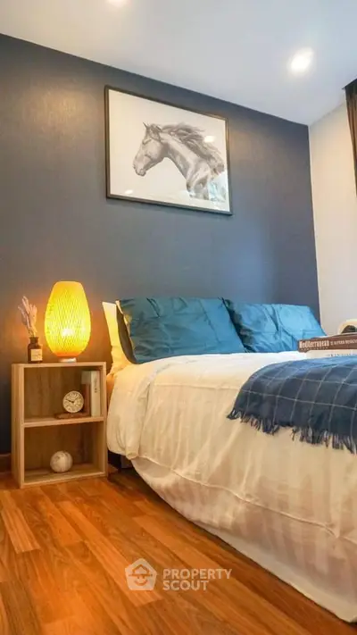 Cozy bedroom with stylish decor and warm lighting, featuring a horse artwork and wooden flooring.