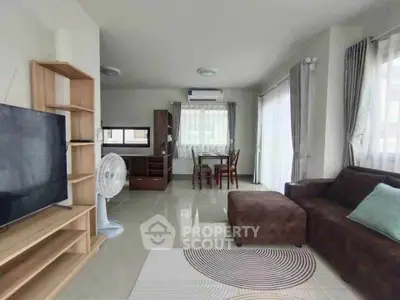 Modern living room with cozy sofa, TV, and dining area in open layout.