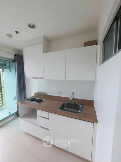 Modern minimalist kitchen with sleek white cabinets and wooden countertop