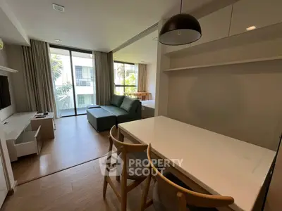 Modern living room with open layout and natural light, featuring a cozy sofa and dining area.