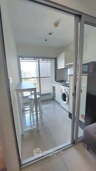 Modern kitchen with washing machine and city view, featuring sleek design and natural light.
