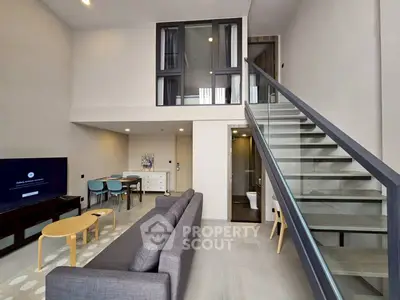 Modern loft-style living room with high ceiling and sleek staircase