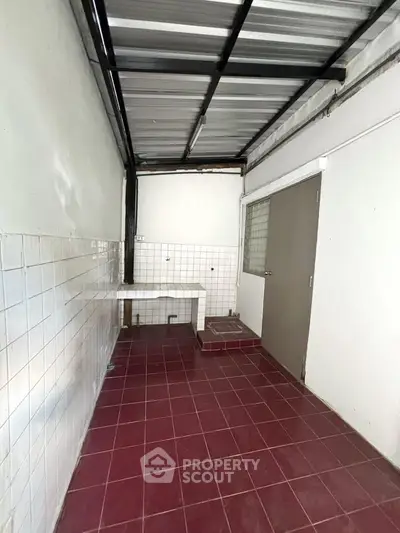 Spacious utility area with tiled flooring and metal roof, ideal for storage or laundry setup.