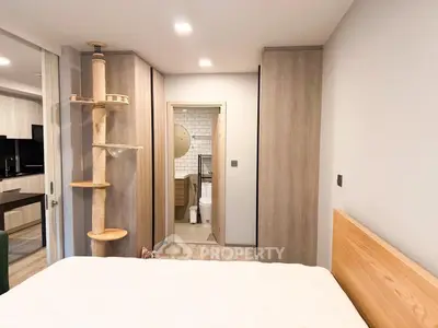 Modern bedroom with ensuite bathroom and stylish cat tree, featuring sleek wooden finishes.