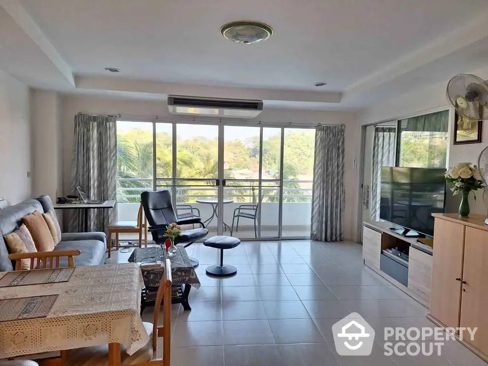 Spacious living room with ample natural light, modern furniture, and a serene balcony view, perfect for relaxation and entertainment.