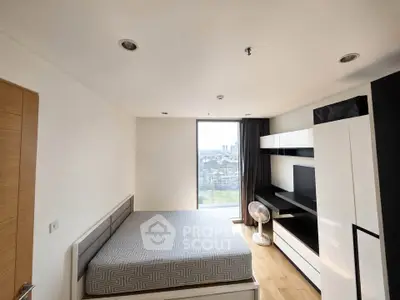 Modern bedroom with large window offering stunning city view, sleek furniture, and wooden flooring.