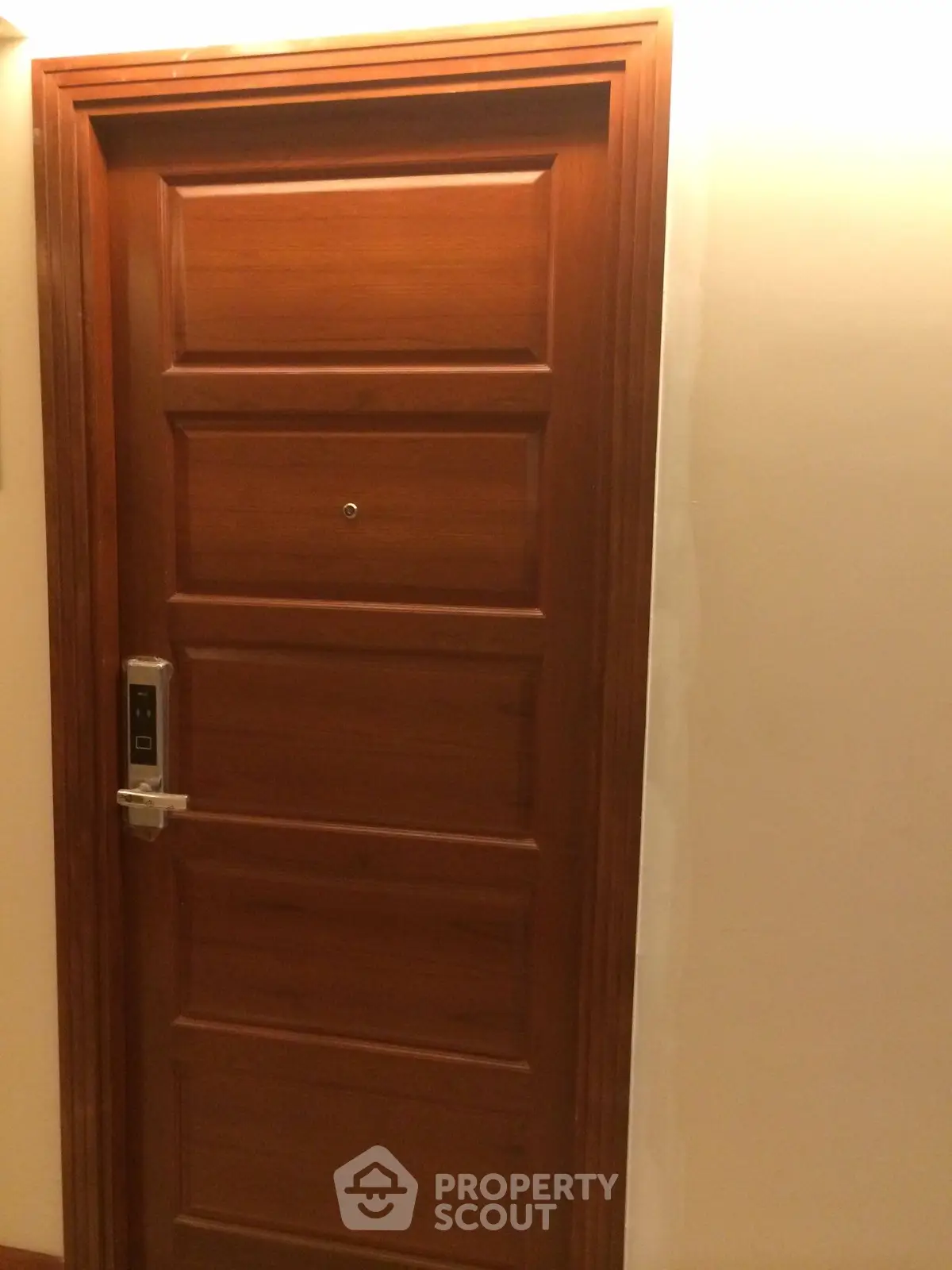 Elegant wooden apartment door with modern electronic lock in a well-lit hallway.