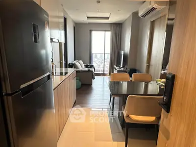 Modern apartment interior with sleek kitchen and cozy living area, featuring large windows and stylish furniture.