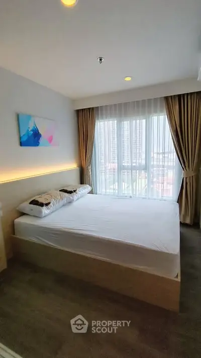 Modern bedroom with large window and city view, featuring stylish decor and natural light.