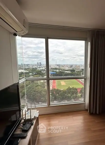 Stunning city view from modern living room with large window and wooden flooring.