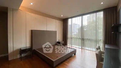 Spacious bedroom with large windows and modern furnishings in a luxury apartment.