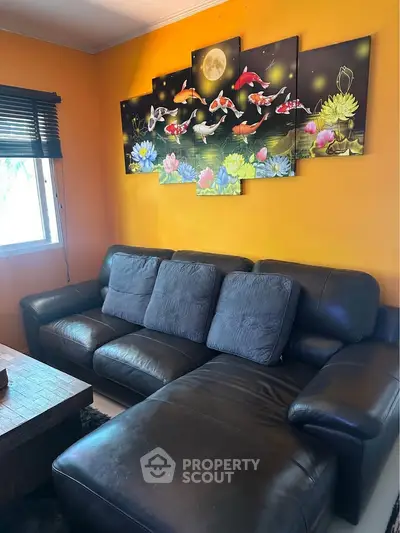 Stylish living room with leather sectional sofa and vibrant koi fish wall art on a bright orange wall.