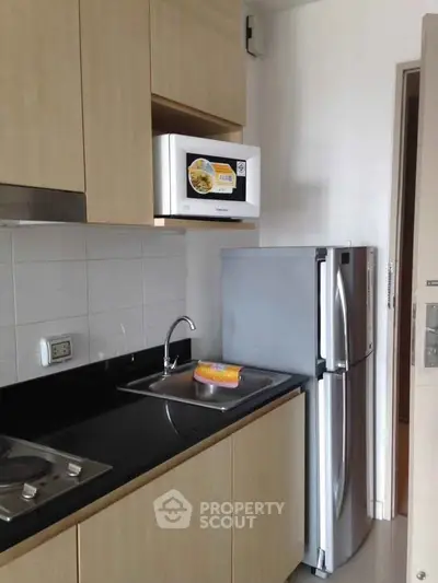 Modern kitchen with sleek cabinets, stainless steel fridge, and microwave, perfect for urban living.