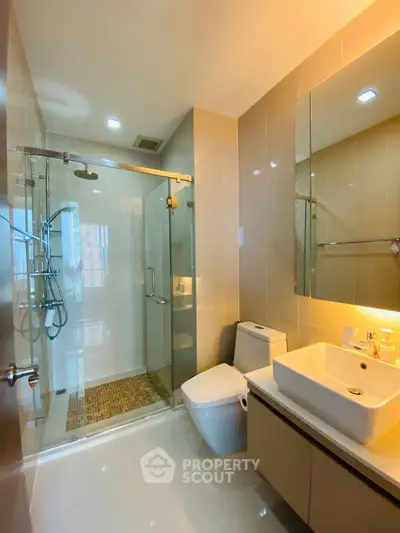 Modern bathroom with glass shower and sleek fixtures in a contemporary apartment.