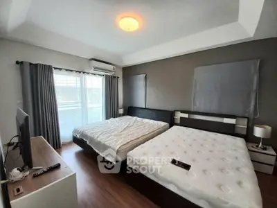 Spacious bedroom with two beds and modern decor, featuring large windows and natural light.