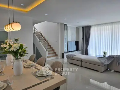 Luxurious open-plan living room with elegant dining area and modern staircase, perfect for stylish living.