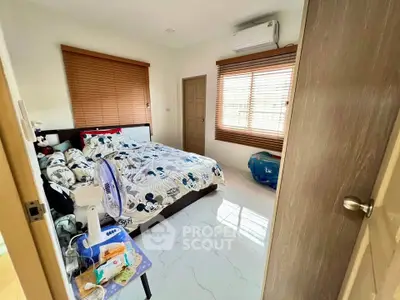 Cozy bedroom with stylish decor and natural light, featuring a comfortable bed and modern air conditioning.