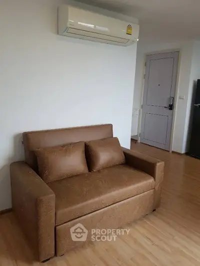 Cozy living room with brown leather sofa and modern air conditioning unit.