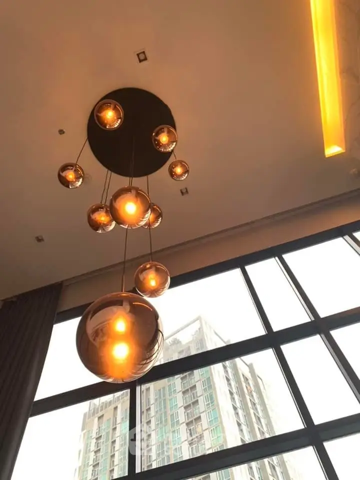 Modern high-rise apartment with stylish pendant lighting and large windows offering city views.