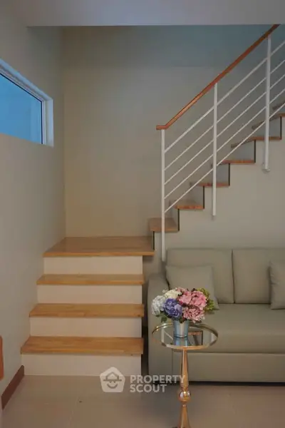 Stylish modern living room with staircase and elegant sofa, perfect for cozy gatherings.