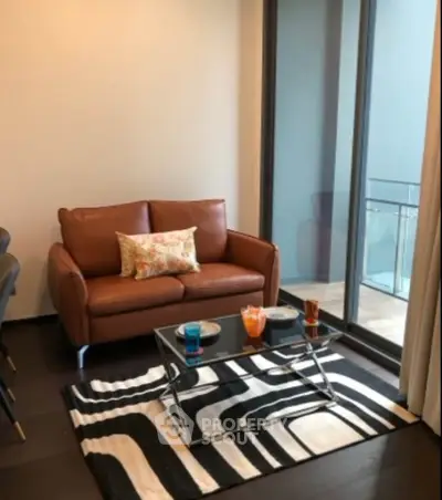 Modern living room with stylish furniture and large glass doors leading to a balcony.