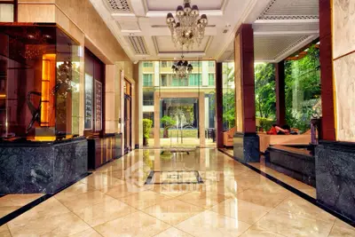 Luxurious building entrance with marble floors and elegant chandeliers, offering a grand welcome.