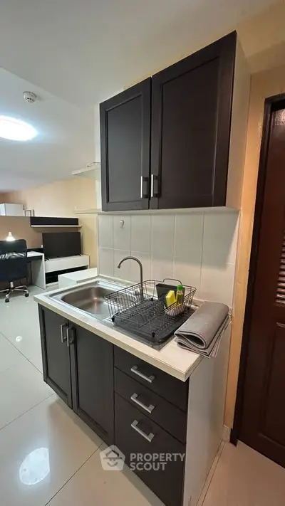 Modern compact kitchen with sleek cabinetry and stainless steel sink in a cozy apartment.