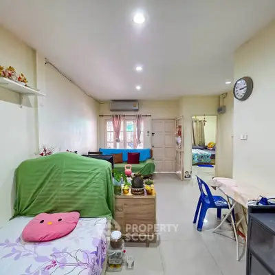 Cozy living room with bright decor and natural light, featuring a comfortable seating area and a glimpse into the bedroom.