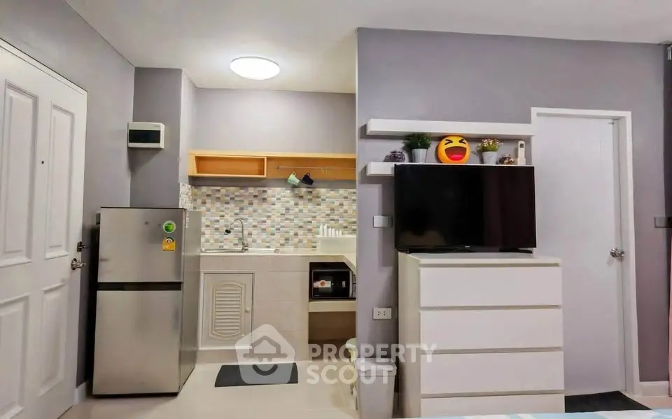 Modern compact kitchen with sleek appliances and stylish decor in a cozy apartment setting.