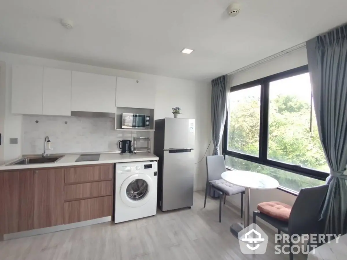 Modern kitchen with washing machine and dining area in bright apartment