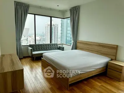 Spacious bedroom with city view, wooden flooring, and modern furniture in a high-rise apartment.