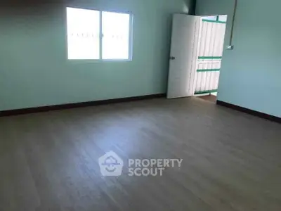 Spacious empty room with wooden flooring and natural light