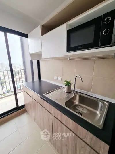 Modern kitchen with sleek cabinetry and city view from balcony.