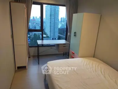 Modern bedroom with city view, featuring stylish furniture and large window for natural light.