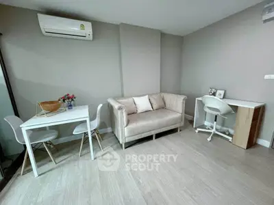 Modern living room with stylish furniture and neutral tones, featuring a cozy sofa and workspace.