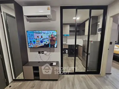 Modern apartment interior with sleek kitchen and living area featuring TV and air conditioning.